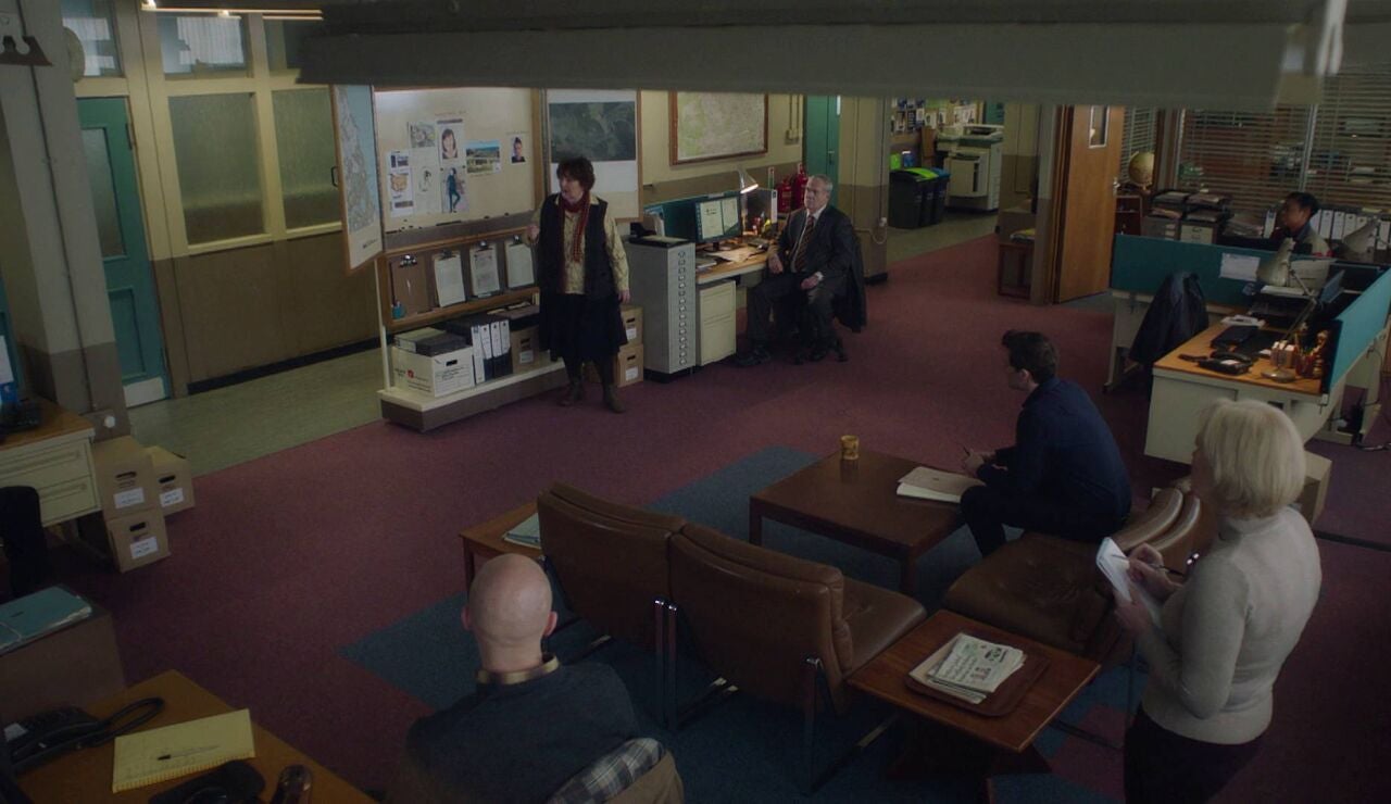 Vera informa a su equipo sobre el asesinato de una profesora